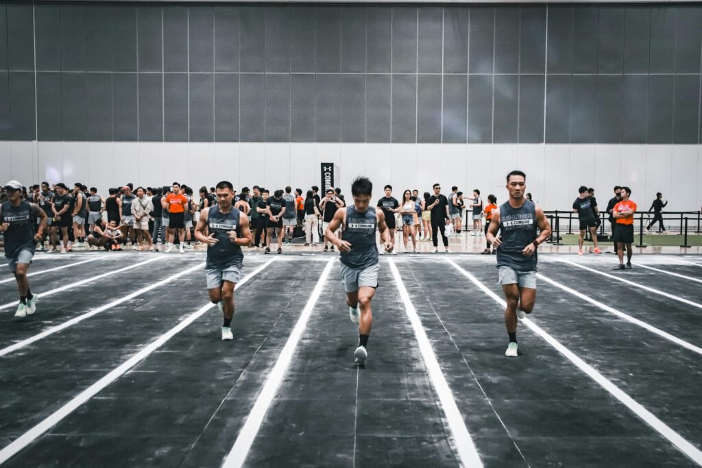 Athletes run in an indoor competition with spectators watching, showcasing endurance and sportsmanship.